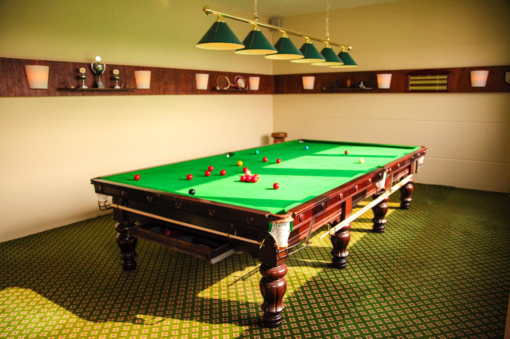 Snookertisch im separaten Raum mit grünen Lampenschirmen