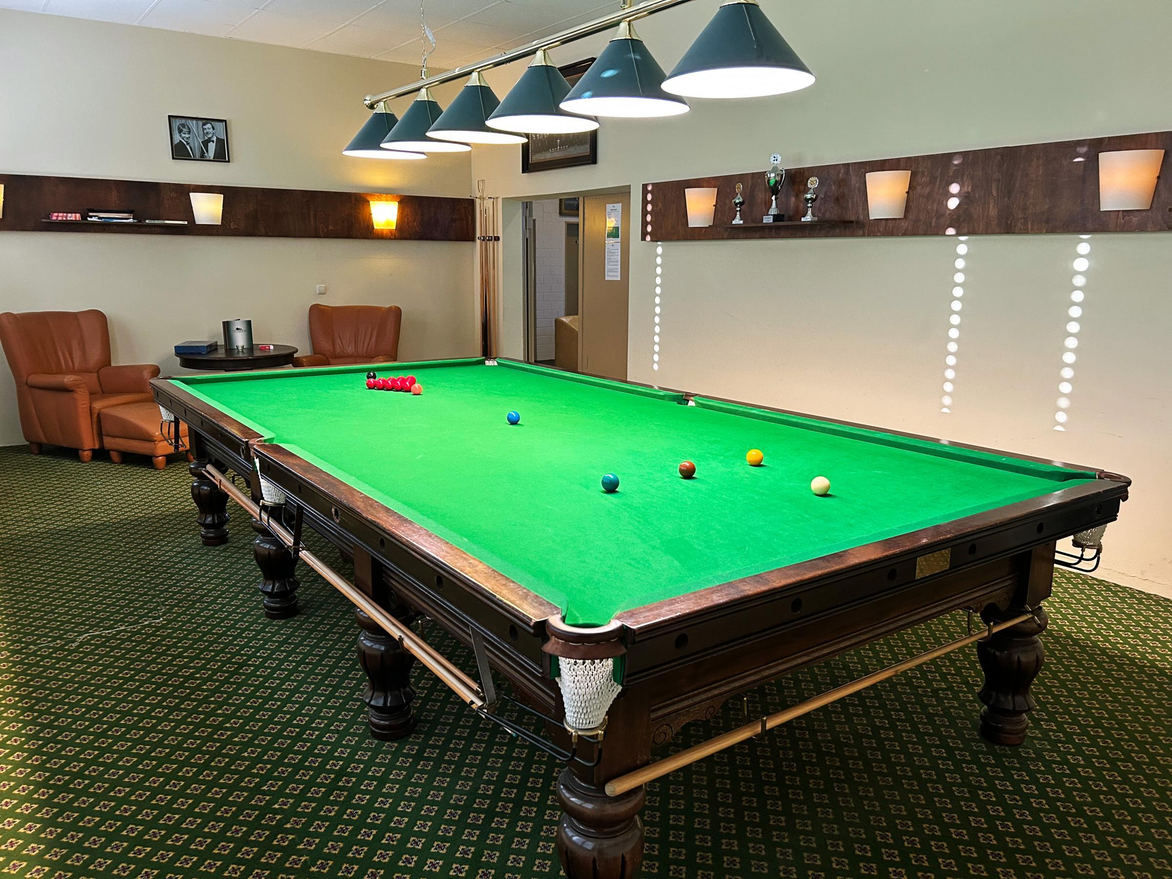 Snookerraum mit Turniertisch, grünen Lampenschirmen und Ledersesseln