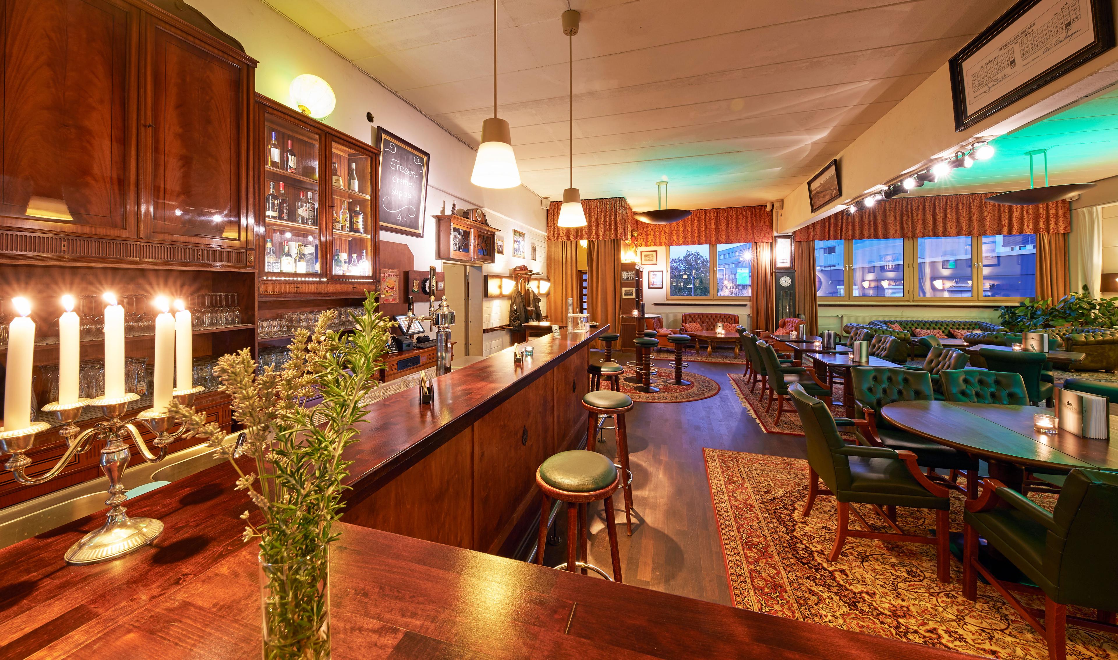 Bar des Clubhouse mit Kerzenleuchter, Barhockern und Chesterfield-Ecke